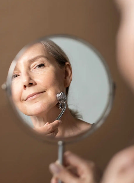 Anti-idade – mulher madura a cuidar da pele do rosto com rolo facial.